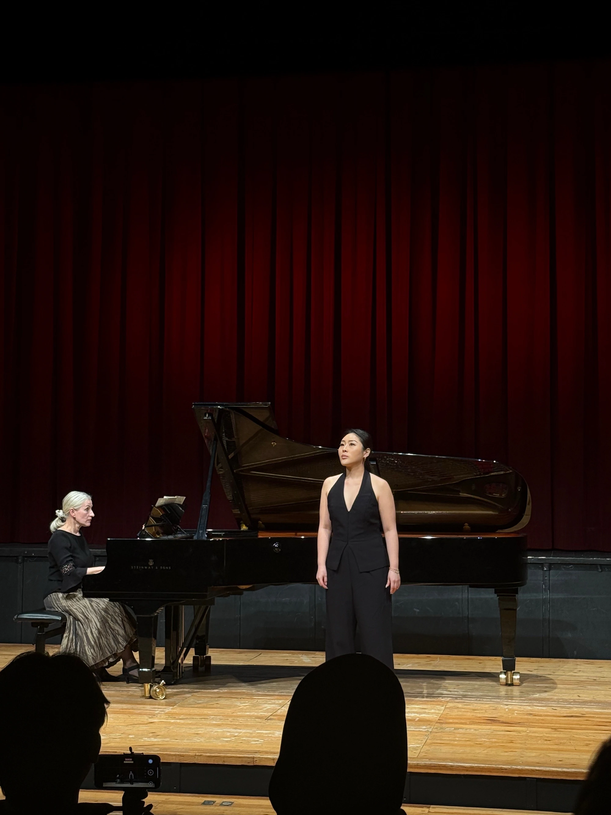 Daoun Jung standing beside a grand piano with her accompanist during a recital